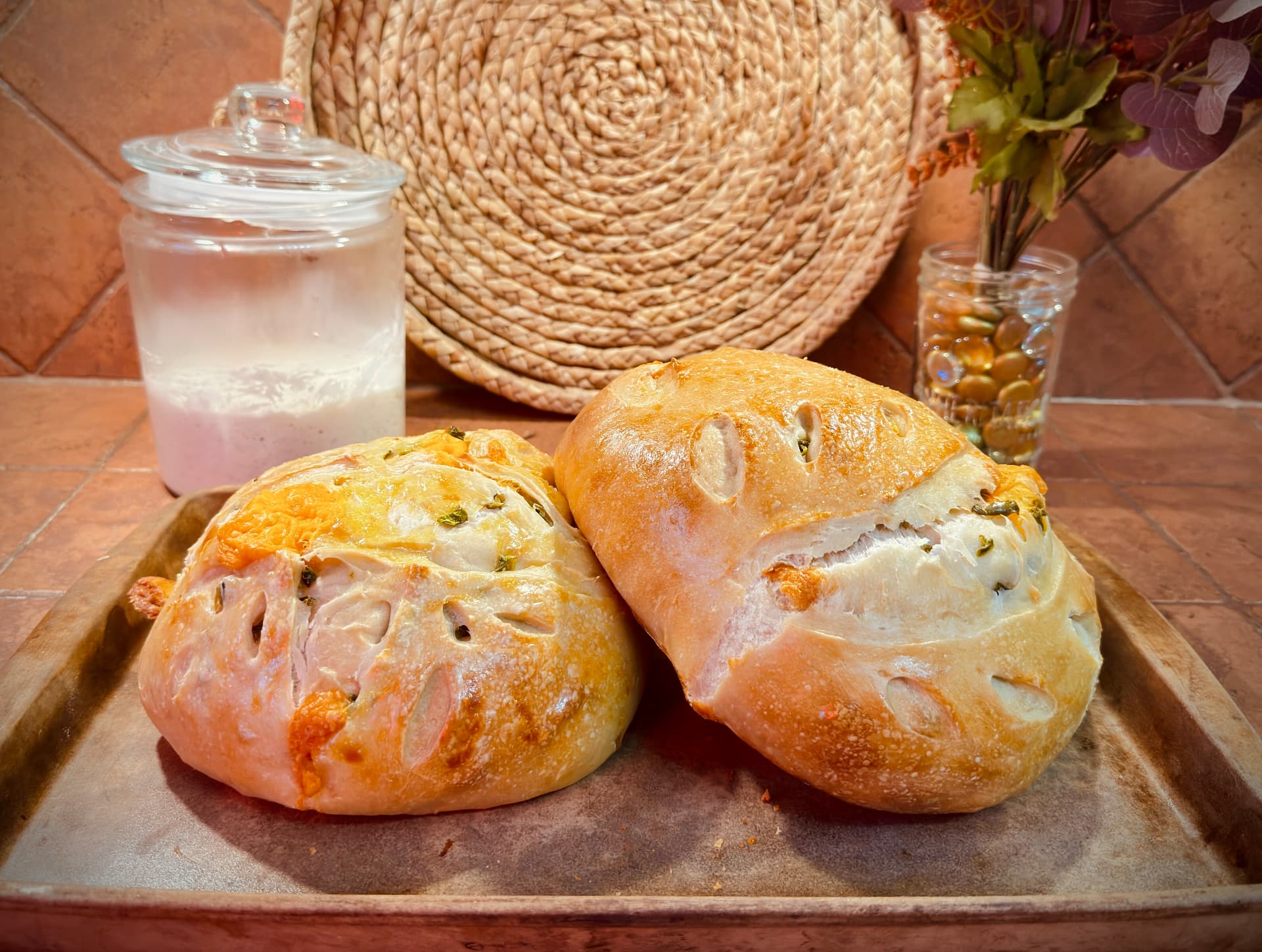 Two jalapeño cheddar sourdough boules on a worn baking tray